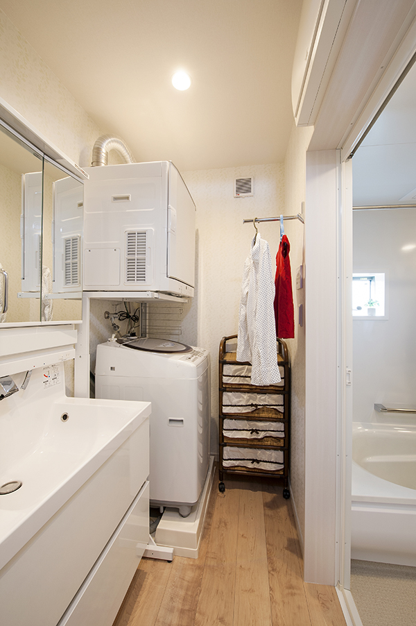 乾燥の早いガス乾燥機のある洗面室。服をかけるフックでスペースを活用